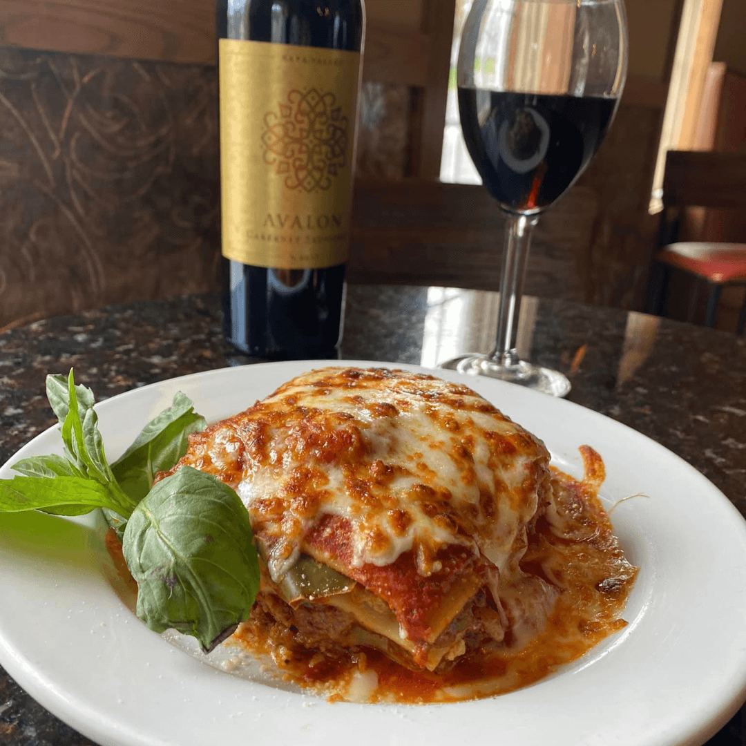 plate of lasagna with a glass of red wine